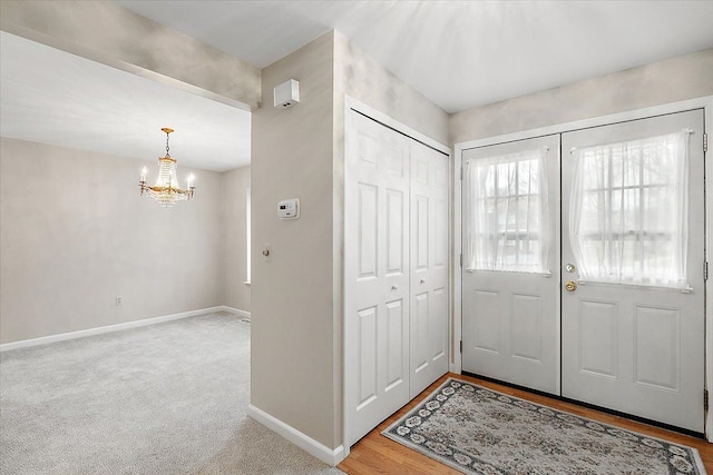 carpeted entryway with an inviting chandelier