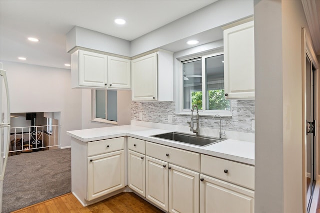 kitchen with white cabinetry, sink, backsplash, kitchen peninsula, and light hardwood / wood-style floors