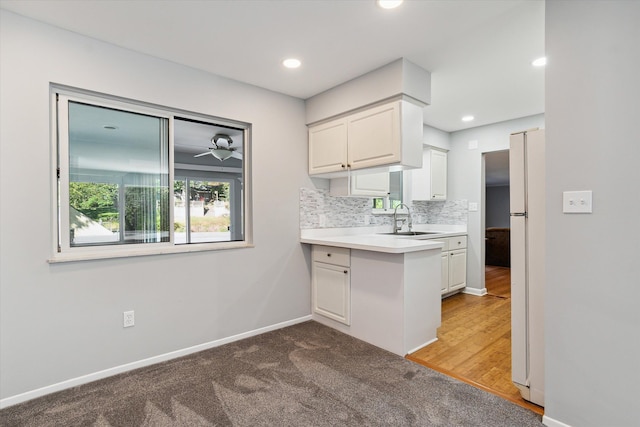 kitchen with dark carpet, white cabinets, white refrigerator, sink, and tasteful backsplash