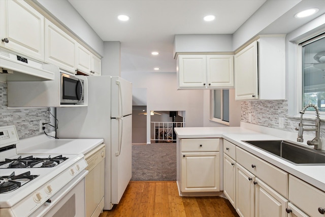 kitchen featuring sink, light hardwood / wood-style flooring, kitchen peninsula, white appliances, and custom exhaust hood