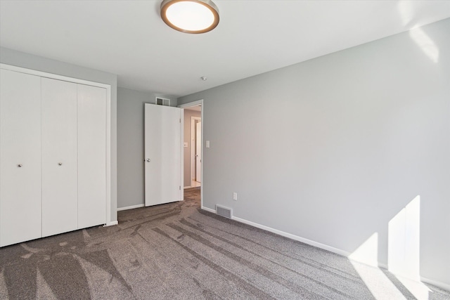 unfurnished bedroom with dark colored carpet and a closet