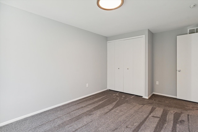 unfurnished bedroom with a closet and dark colored carpet