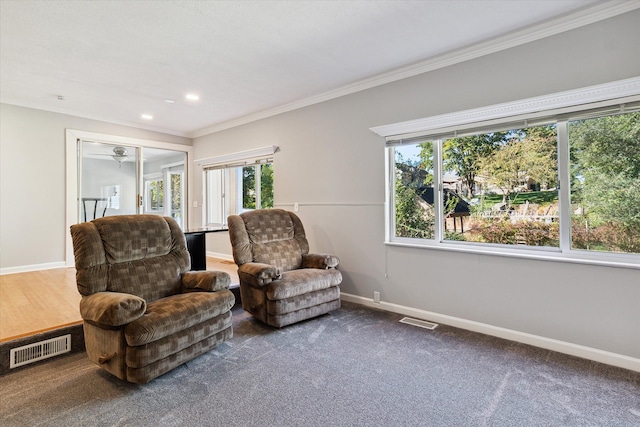 living area featuring a wealth of natural light, crown molding, and carpet floors