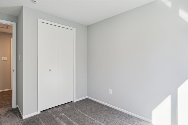 unfurnished bedroom featuring dark carpet and a closet