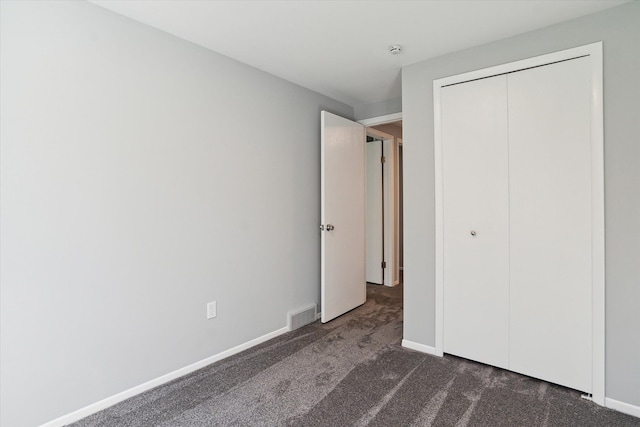 unfurnished bedroom featuring dark colored carpet and a closet