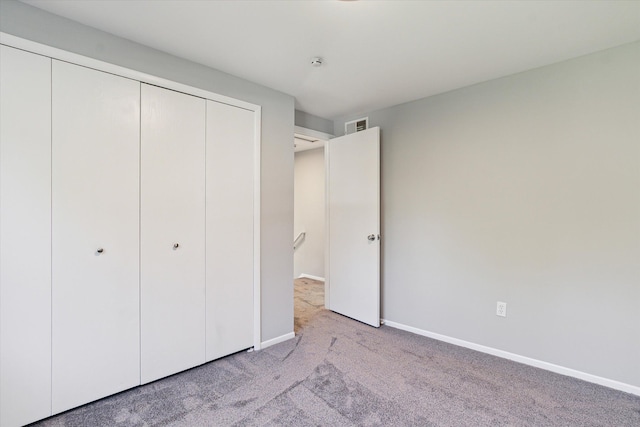 unfurnished bedroom featuring light carpet and a closet