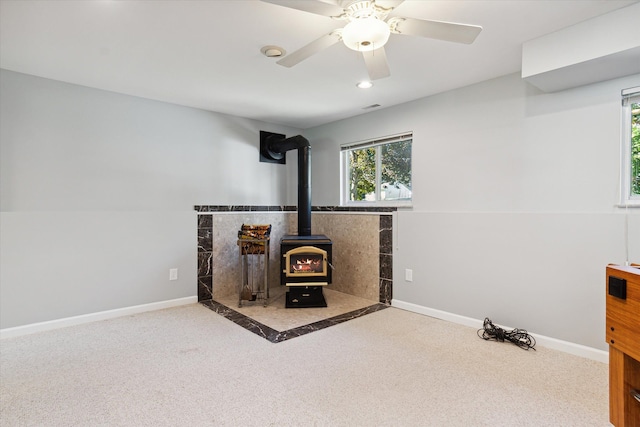 exercise room with a wood stove, ceiling fan, and carpet