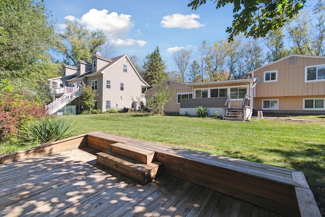 rear view of house with a sunroom, a deck, and a yard