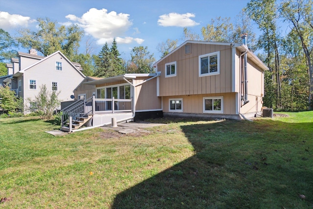 rear view of house featuring a yard, central AC unit, and a sunroom