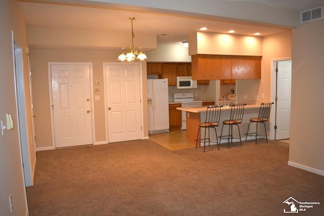 kitchen featuring carpet, white appliances, pendant lighting, a notable chandelier, and a breakfast bar area