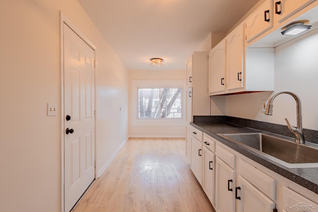 kitchen with white cabinetry, sink, and light hardwood / wood-style flooring