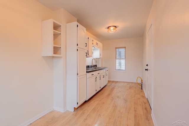 kitchen with light hardwood / wood-style floors, white cabinetry, and sink