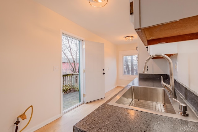 kitchen with light hardwood / wood-style flooring, white cabinetry, and sink