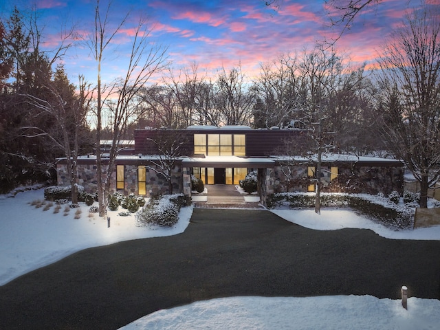 mid-century modern home featuring stone siding and a lawn