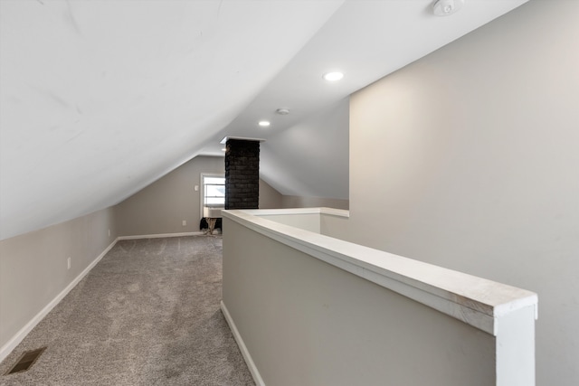 corridor featuring lofted ceiling and carpet flooring