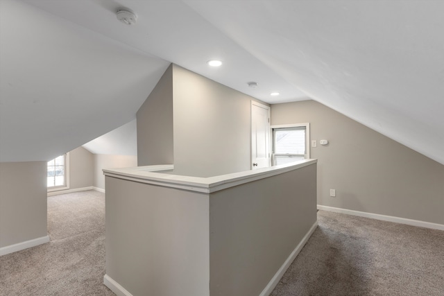 bonus room with lofted ceiling and light colored carpet