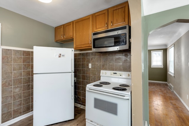 kitchen with decorative backsplash, wood-type flooring, and white appliances