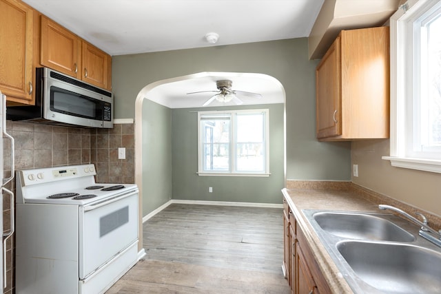 kitchen featuring ceiling fan, decorative backsplash, plenty of natural light, electric range, and sink