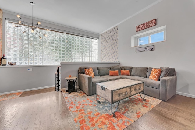 living room featuring light wood-type flooring, a notable chandelier, and crown molding