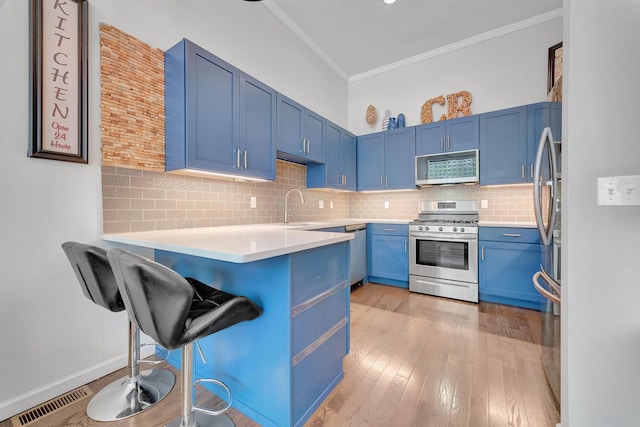 kitchen with kitchen peninsula, light hardwood / wood-style flooring, stainless steel appliances, a breakfast bar, and blue cabinetry