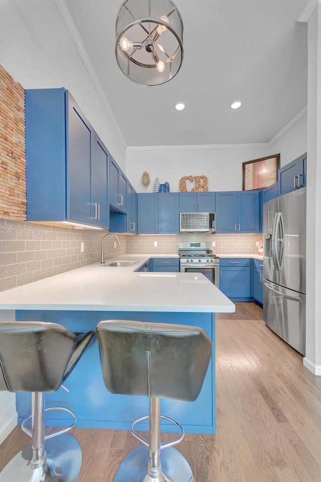 kitchen with appliances with stainless steel finishes, a breakfast bar, blue cabinetry, and kitchen peninsula