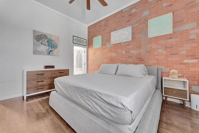 bedroom with ceiling fan, dark hardwood / wood-style floors, crown molding, and brick wall