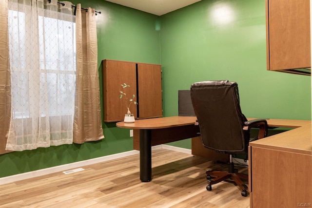 home office with light hardwood / wood-style flooring