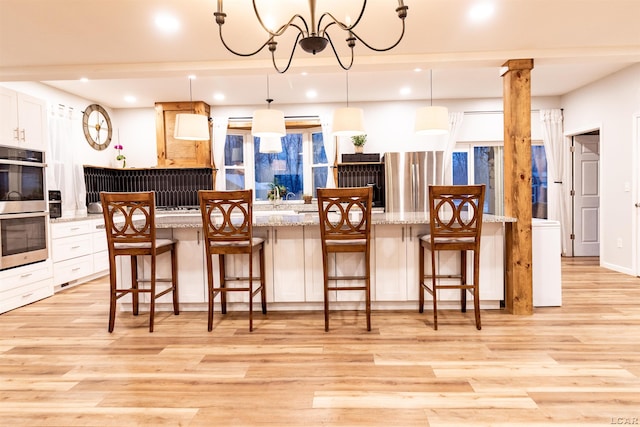 kitchen with a center island, white cabinets, a kitchen breakfast bar, hanging light fixtures, and stainless steel appliances