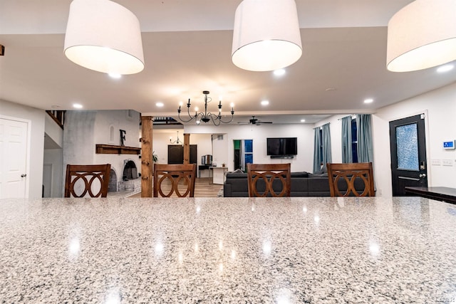 kitchen featuring ceiling fan with notable chandelier and light stone countertops