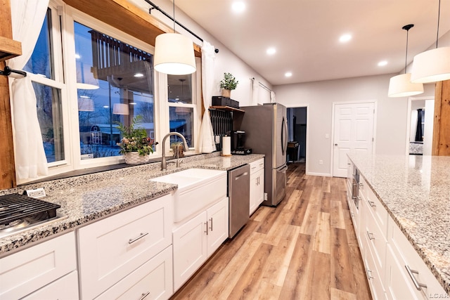 kitchen featuring white cabinets, decorative light fixtures, sink, and stainless steel appliances