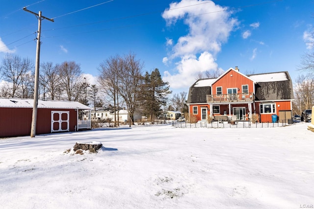 yard layered in snow with a balcony and a storage unit