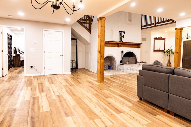 living room featuring a chandelier, light wood-type flooring, and a brick fireplace