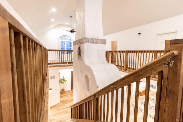 stairway with ceiling fan, hardwood / wood-style floors, and high vaulted ceiling