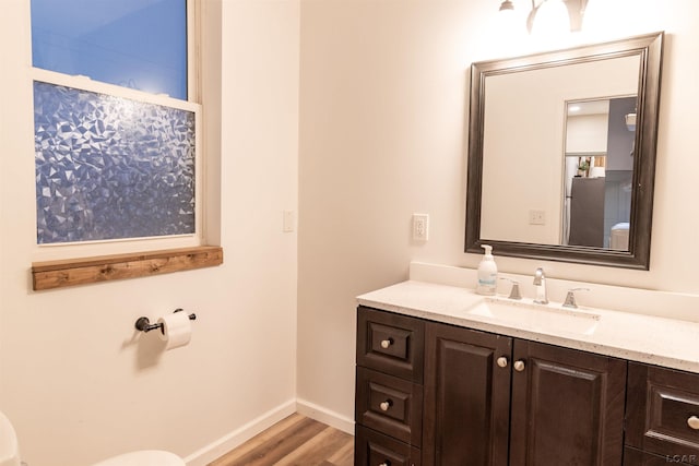 bathroom featuring vanity, wood-type flooring, and toilet