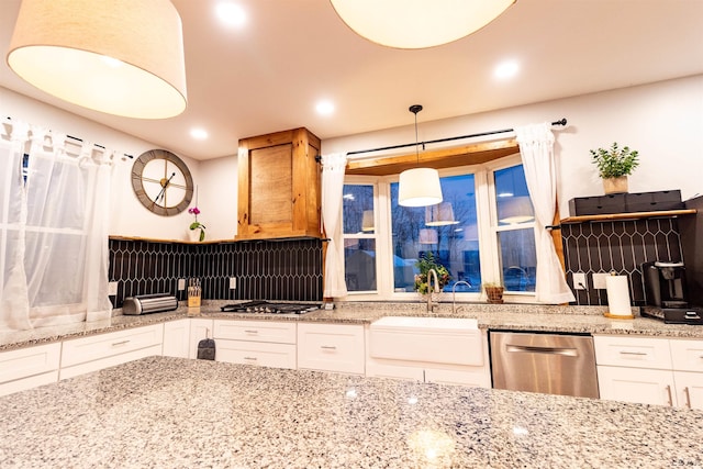 kitchen with light stone countertops, sink, hanging light fixtures, white cabinets, and appliances with stainless steel finishes