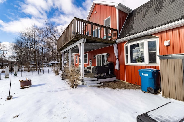 snow covered back of property with a deck