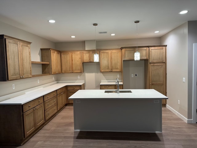 kitchen featuring dark hardwood / wood-style flooring, a center island with sink, pendant lighting, and sink