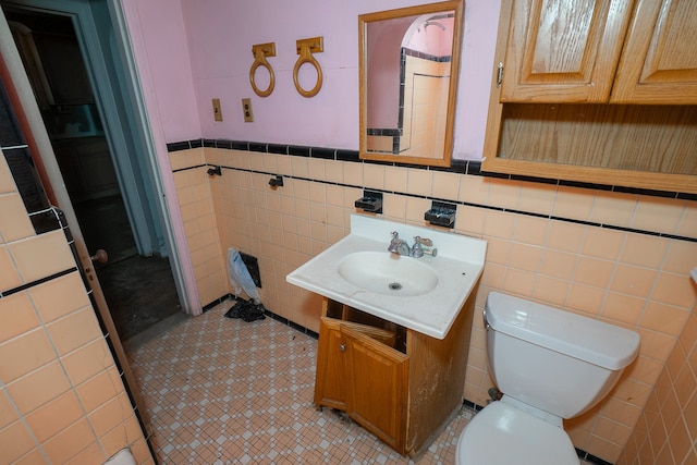 bathroom featuring vanity, toilet, and tile walls