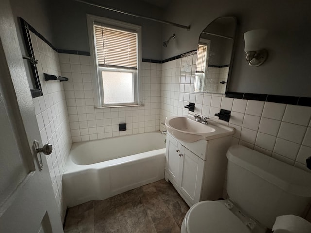 full bathroom featuring toilet, vanity, tile walls, and tiled shower / bath