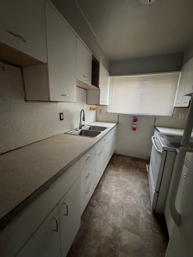 kitchen featuring white range with electric cooktop, white cabinetry, and sink