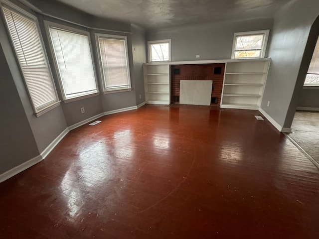 unfurnished living room with plenty of natural light and a fireplace