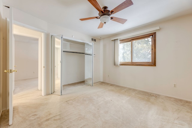 unfurnished bedroom featuring ceiling fan, light colored carpet, and a closet