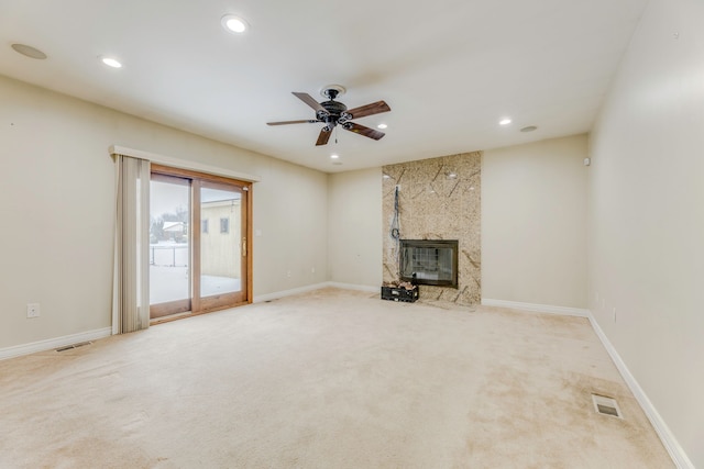 unfurnished living room featuring a fireplace, light colored carpet, and ceiling fan