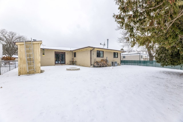 snow covered back of property featuring central AC