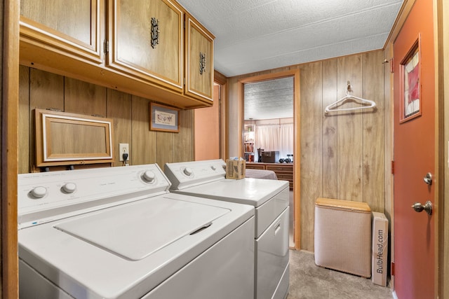 laundry area with washing machine and dryer, cabinets, and wooden walls