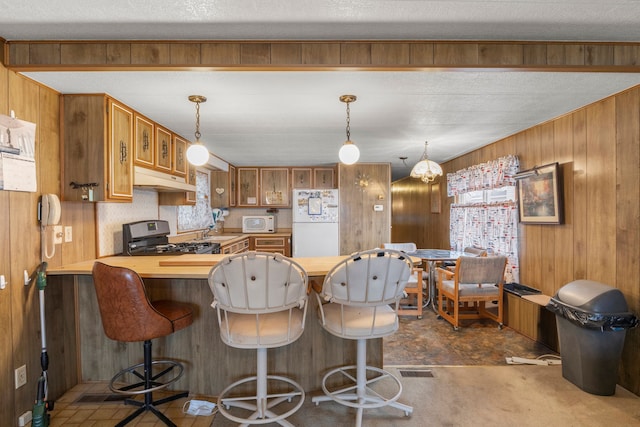 kitchen with kitchen peninsula, wooden walls, white appliances, and a textured ceiling