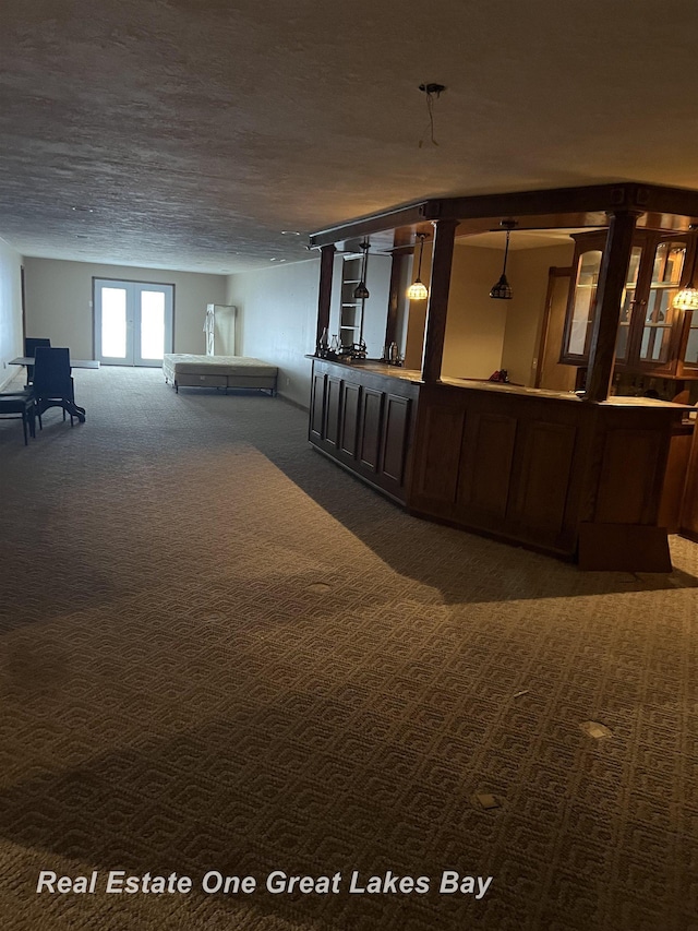 interior space featuring dark colored carpet, a textured ceiling, bar area, and french doors