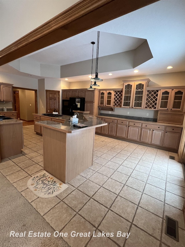 kitchen with pendant lighting, a center island, light tile patterned flooring, and black fridge