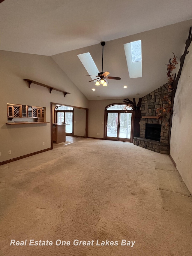 unfurnished living room with a skylight, ceiling fan, a fireplace, and a healthy amount of sunlight