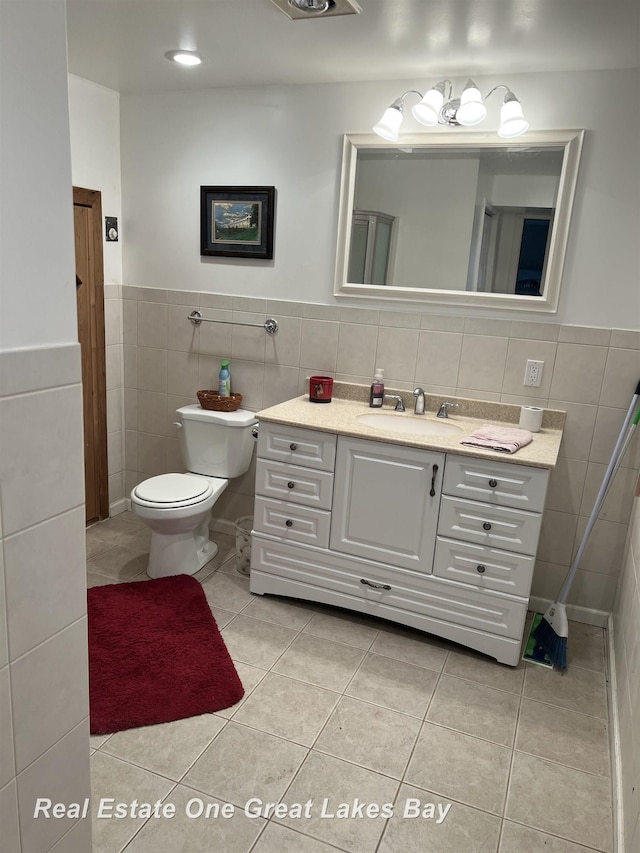 bathroom featuring toilet, vanity, tile patterned floors, and tile walls